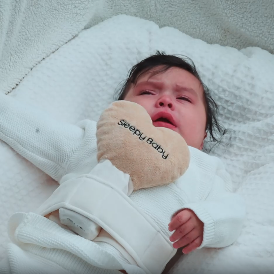 Baby in white outfit lying on bed with soft bedding | Sleepy Baby

