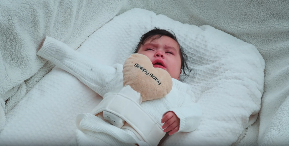 Baby in white outfit lying on bed with soft bedding | Sleepy Baby
